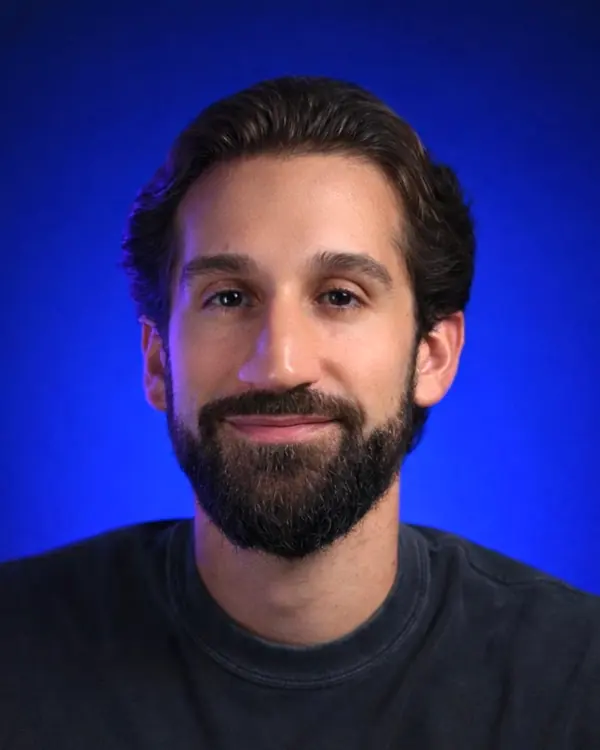 Scott Wills smiling, against a blue backdrop